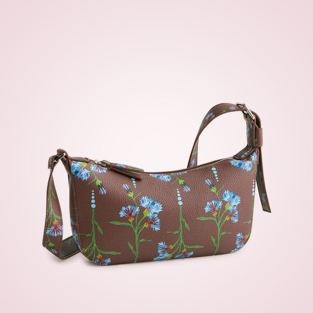 Brown floral faux leather sling crossbody bag on a soft rose background